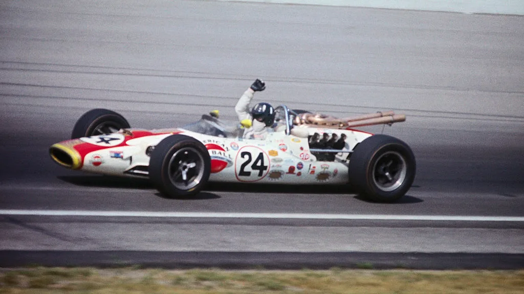 (Original Caption) Graham Hill, with arms raised in victory signal, circling track after winning