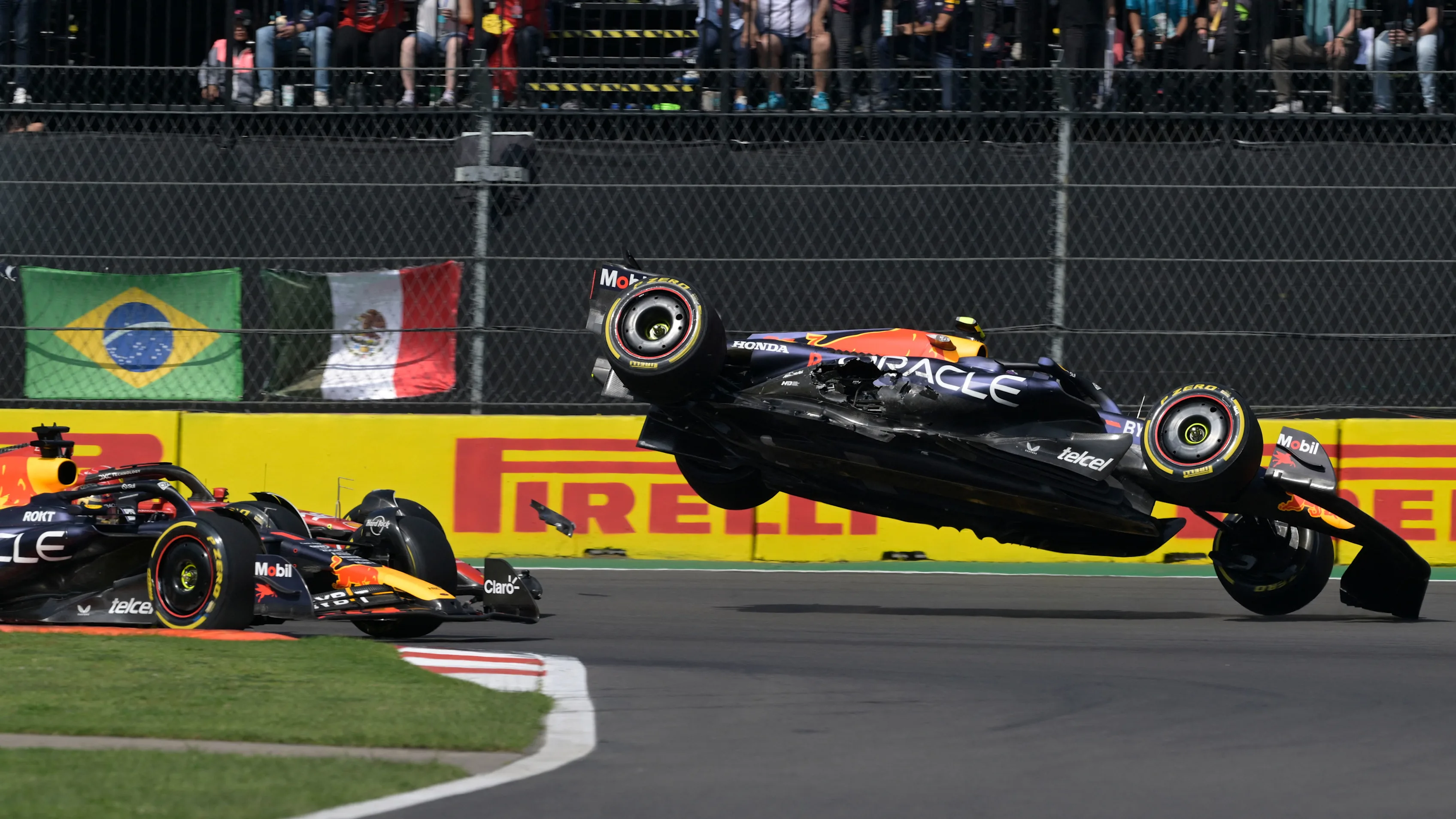 TOPSHOT - Red Bull Racing's Mexican driver Sergio Perez (R) crashes during the start of the Formula