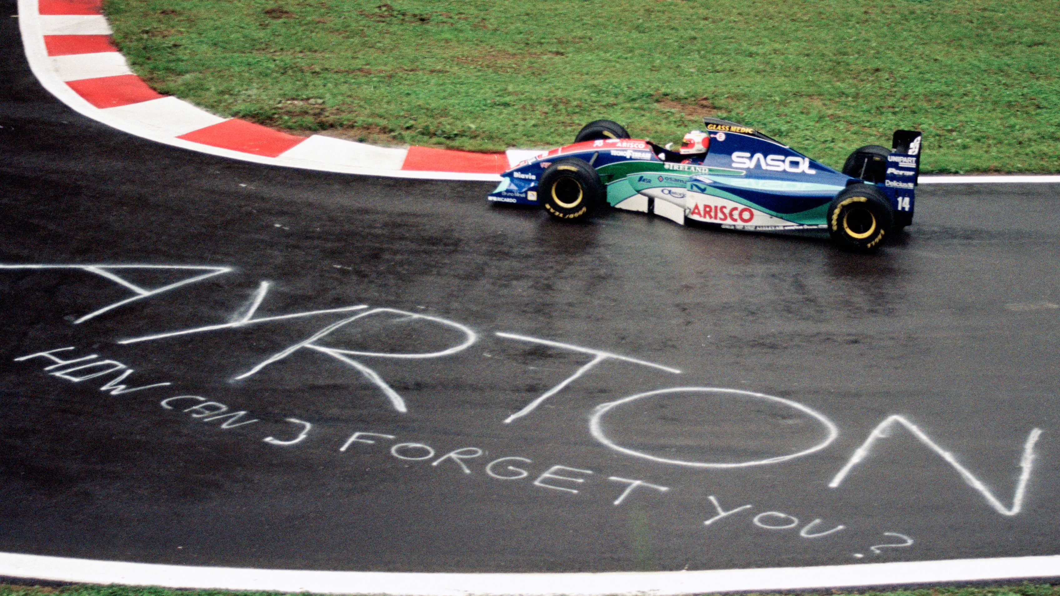 Rubens Barrichello drives the #14 Sasol Jordan Racing Jordan 194 Hart 3.5 V10 past a sign painted