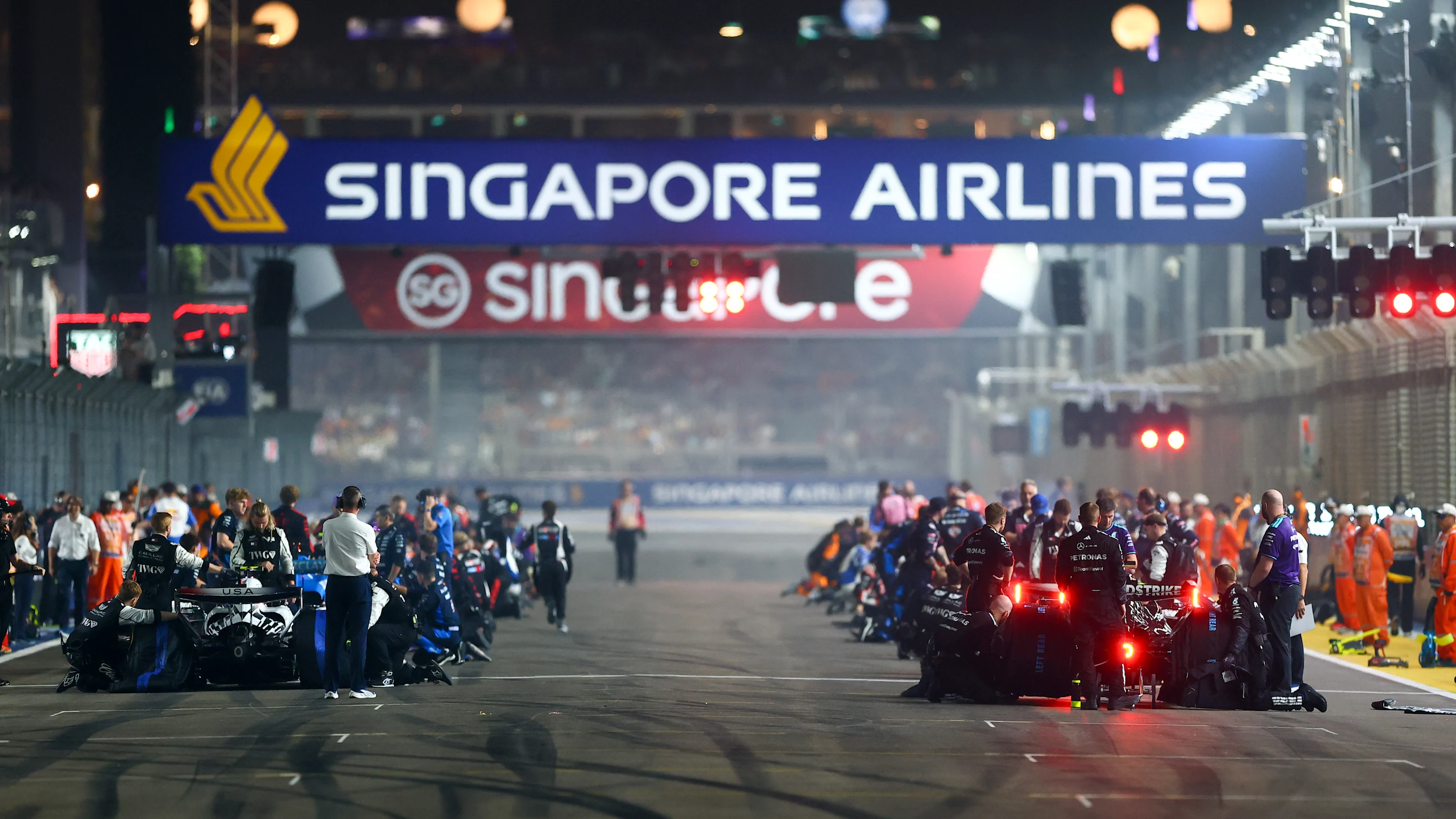 SINGAPORE, SINGAPORE - OCTOBER 11: Mechanics make final preparations on the grid prior to the start
