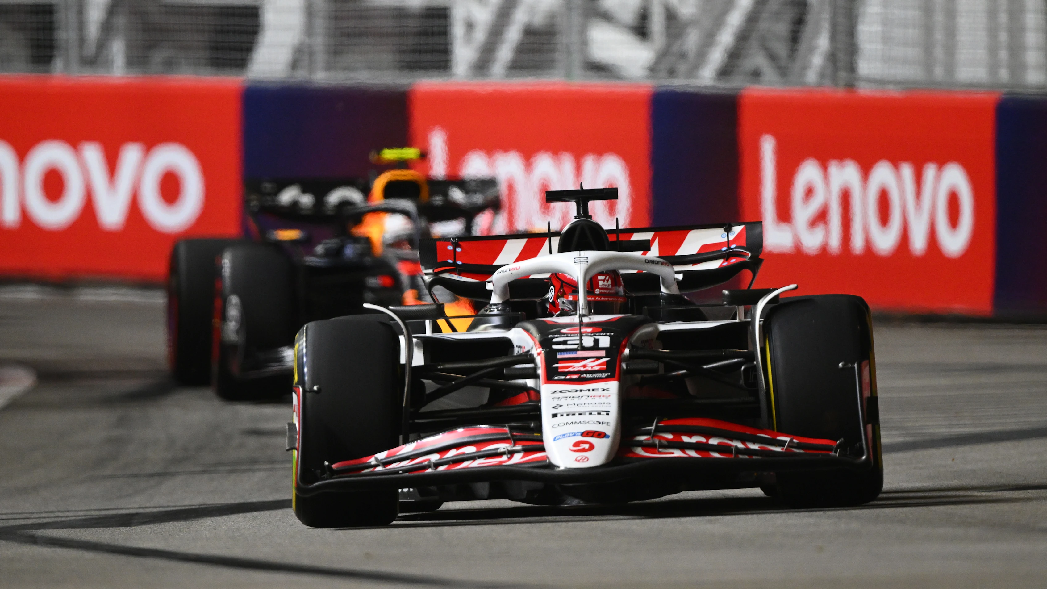 SINGAPORE, SINGAPORE - OCTOBER 05: Esteban Ocon of France driving the (31) Haas F1 VF-25 Ferrari leads Yuki Tsunoda of Japan driving the (22) Oracle Red Bull Racing RB21 on track during to the F1 Grand Prix of Singapore at Marina Bay Street Circuit on October 05, 2025 in Singapore, Singapore. (Photo by Clive Mason/Getty Images)