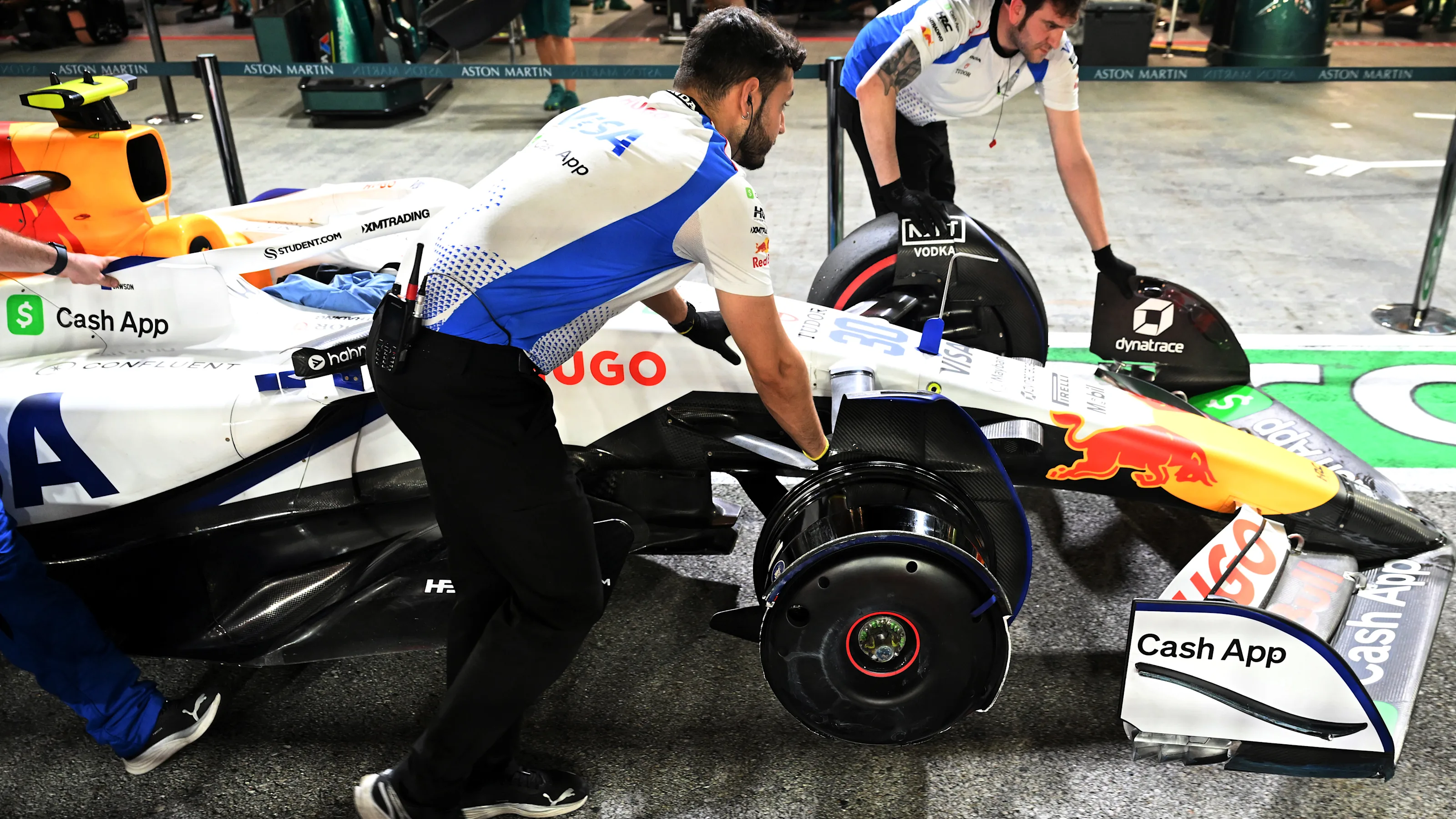 SINGAPORE, SINGAPORE - OCTOBER 03: Mechanics with the damaged car of Liam Lawson of New Zealand