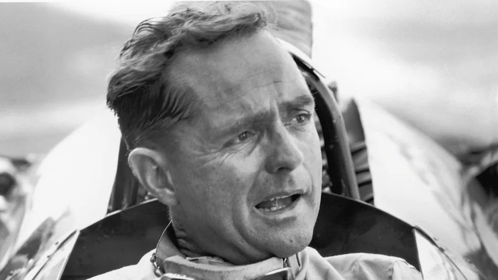 American Grand Prix racing car driver Phil Hill sits in his car and talks to the out-of-frame pit