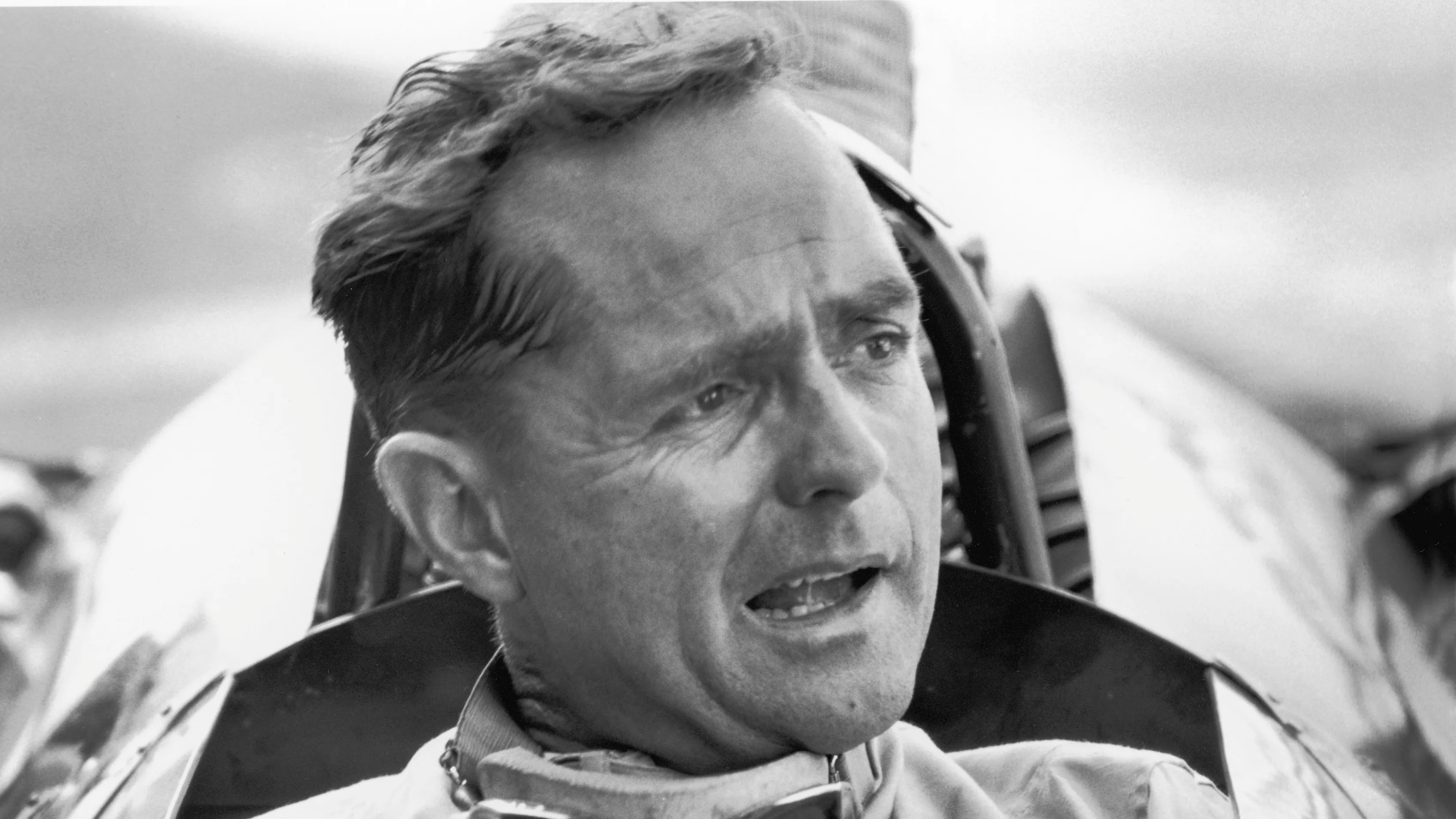 American Grand Prix racing car driver Phil Hill sits in his car and talks to the out-of-frame pit