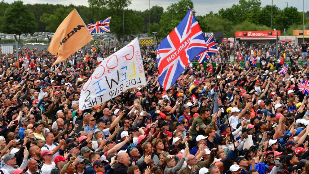 Supporters of Mercedes' British driver Lewis Hamilton cheer him on the podium after his victory in