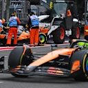 BAKU, AZERBAIJAN - SEPTEMBER 21: Marshals clear away the car of Oscar Piastri of Australia driving the (81) McLaren MCL39 Mercedes, as Lando Norris of Great Britain driving the (4) McLaren MCL39 Mercedes passes them on track during the F1 Grand Prix of Azerbaijan at Baku City Circuit on September 21, 2025 in Baku, Azerbaijan. (Photo by Rudy Carezzevoli/Getty Images)