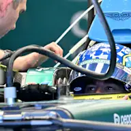 Aston Martin's Spanish driver Fernando Alonso inspects his car with team mechanics in the garage