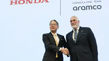 Honda Motor President Toshihiro Mibe (L) shakes hands with Aston Martin F1 executive chairman