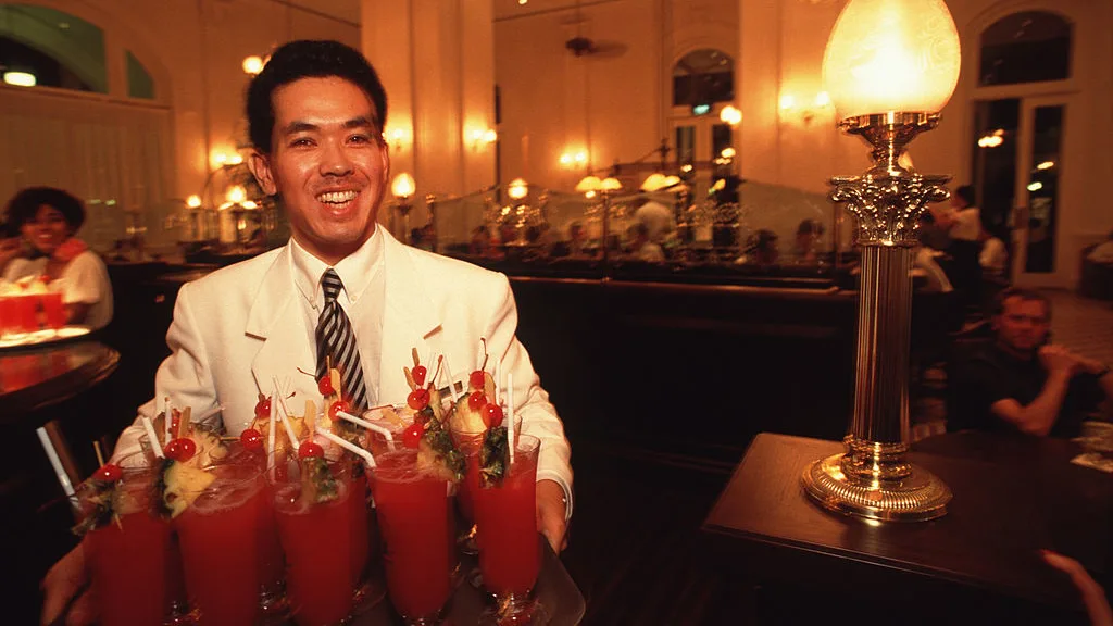 SINGAPORE - 1991/09/01: A waiter carries a tray of "Singapore Slings" in the main bar/pub of the