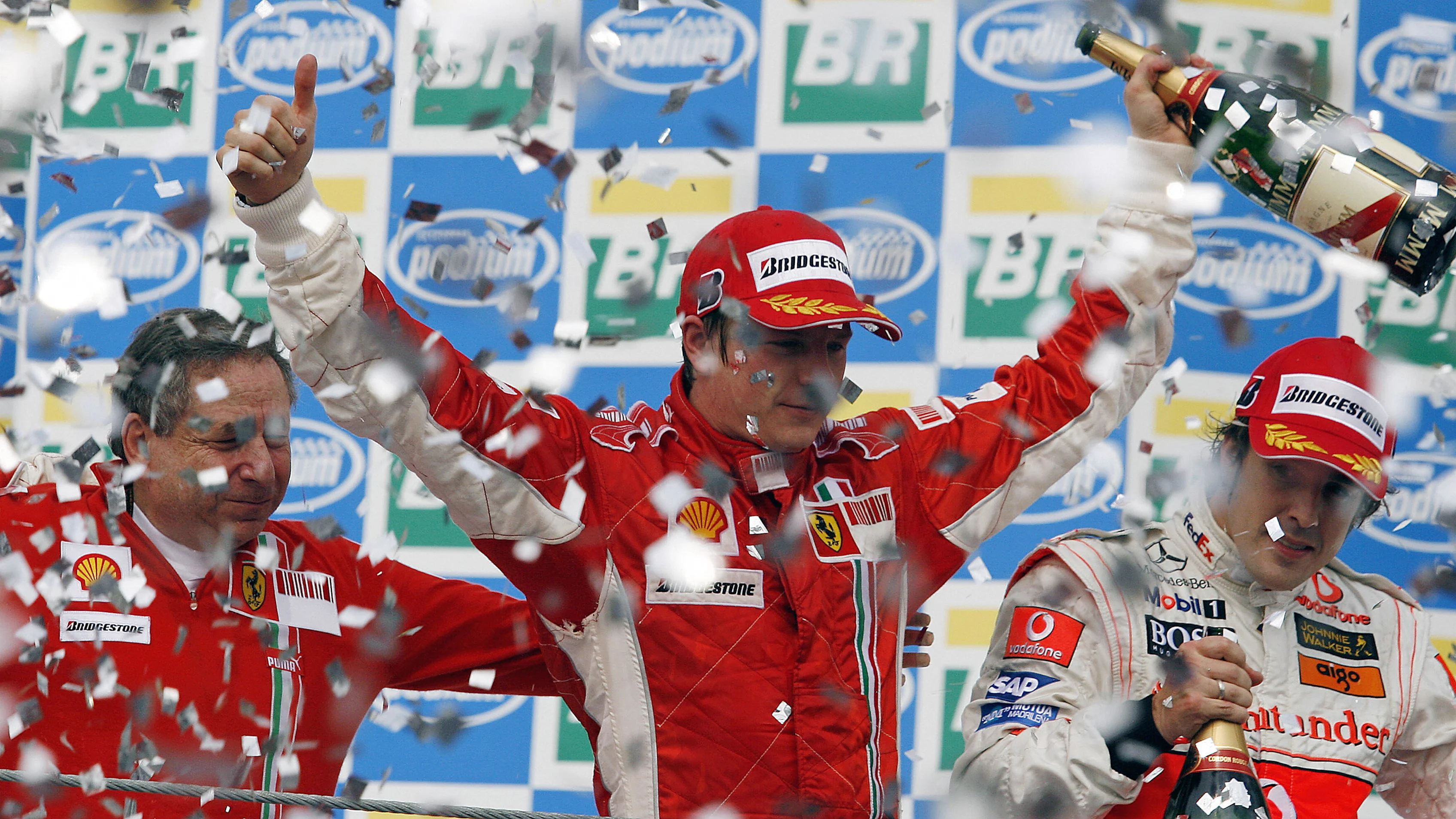 Finnish Formula One driver Kimi Raikkonen (C) celebrates with Ferrari team mananger Jean Todt (L)