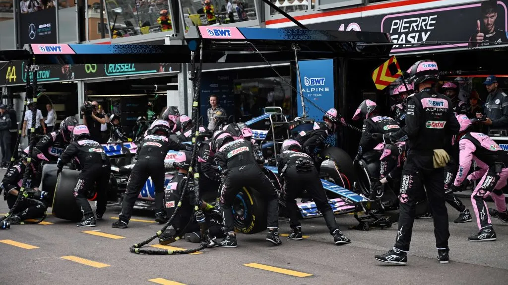 Team members change the wheels of Alpine's French driver Esteban Ocon in the pit lane the