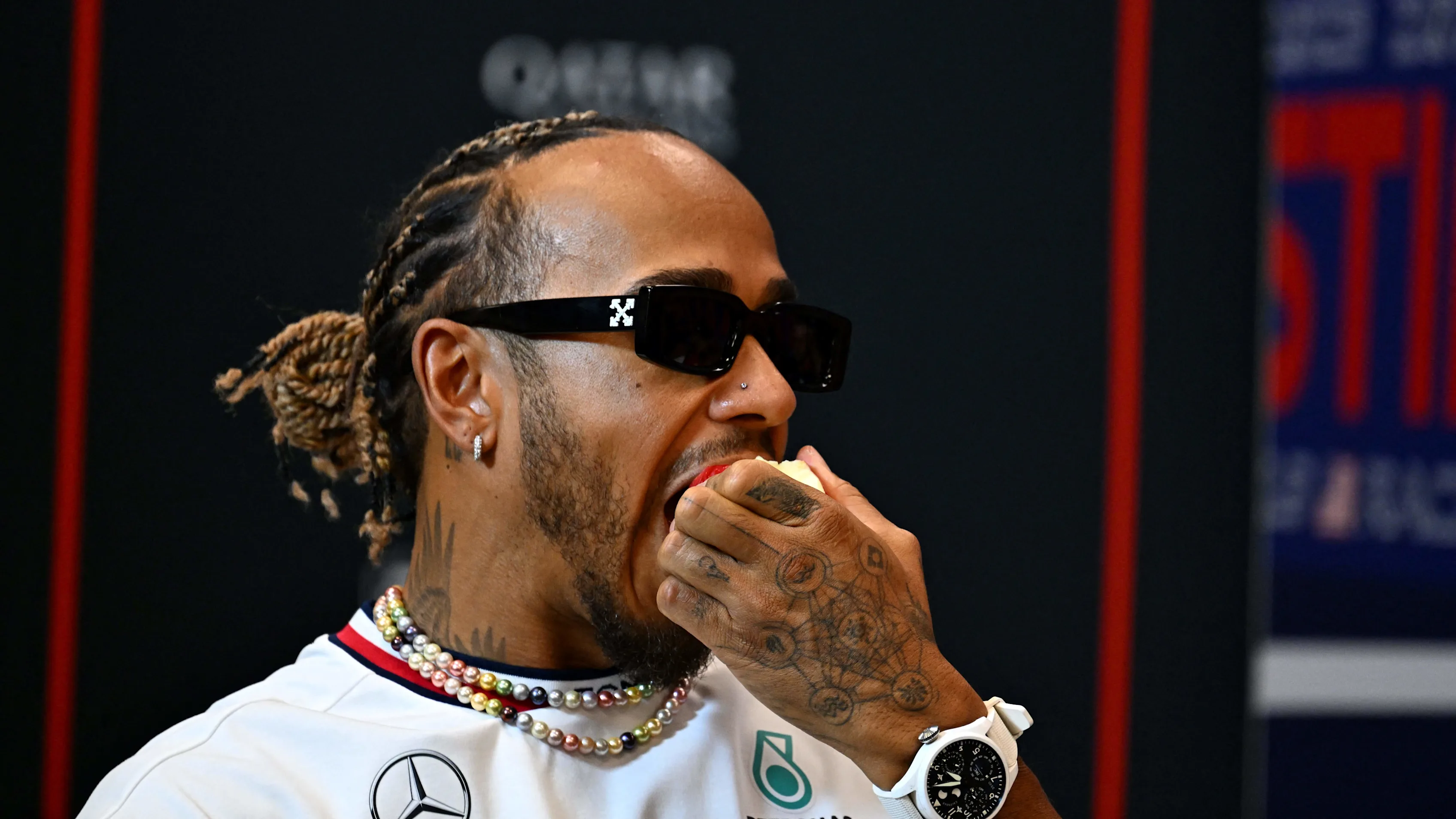 Mercedes' British driver Lewis Hamilton eats an apple as he attends a press conference ahead of the